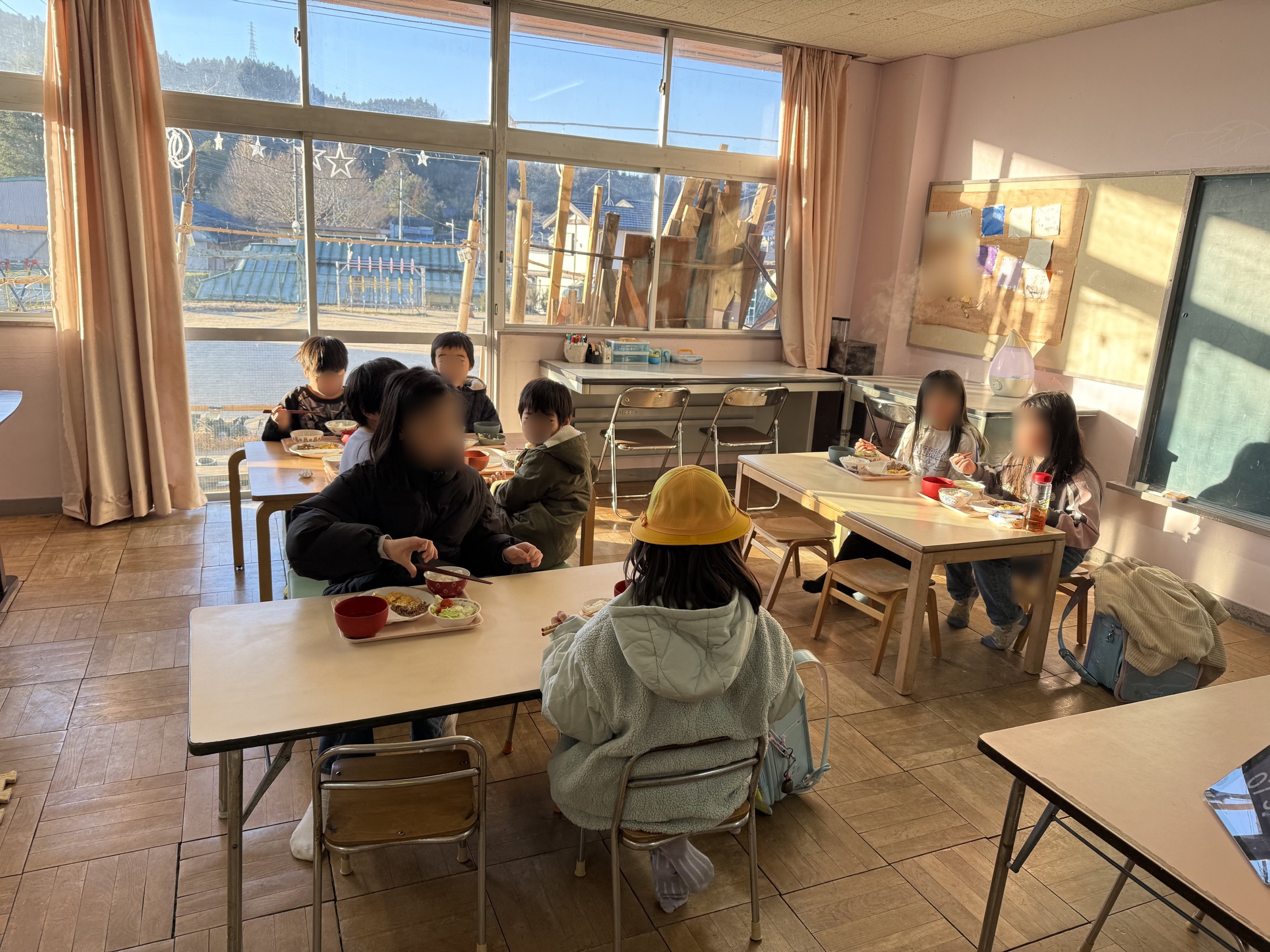 明るい部屋で、子どもや地域の人たちが一緒に食卓を囲む様子